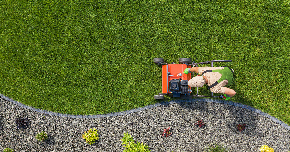 Man pushing a lawn mower over green grass